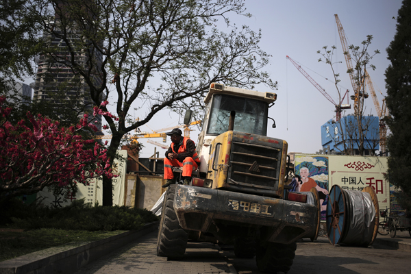 A worker takes his break on a bulldozer parked near a construction site at the Central Business District of Beijing on Monday (AP photo)